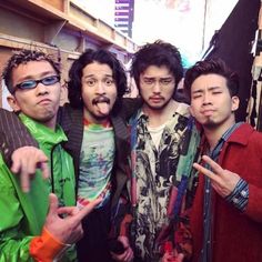 four young men posing for the camera with one pointing at something in front of them