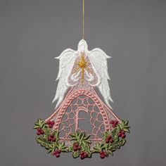 an angel ornament hanging from a string with holly leaves and berries on it