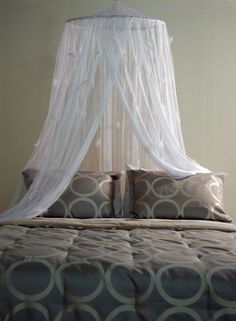 a bed with a white canopy over it's head and pillows on the bottom