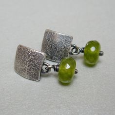 "Rustic sterling silver stud earrings, the small silver square that attaches to a pin has a texture obtained with the fusion of silver dust on the surface. The hanging peridot gives light and movement. The silver has been patinated and then polished to create a contrast of chiaroscuro that highlights the parts in relief. They are very light and comfortable for everyday use. They are also elegant and refined for special occasions. weight 0,07 oz each Dimension 0,39\" x 0,98 Possible small differe Nickel-free Silver Square Pendant Earrings, Square Sterling Silver Earrings, Green Minimalist Sterling Silver Earrings, Minimalist Green Sterling Silver Earrings, Silver Sterling Silver Square Pendant Earrings, Green Modern Sterling Silver Earrings, Modern Green Sterling Silver Earrings, Handmade Square Minimalist Earrings, Minimal Earrings