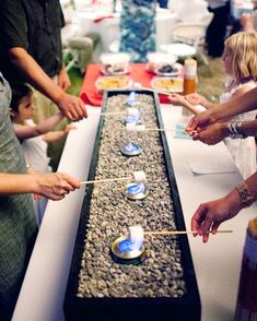 people standing around a table with candles on it