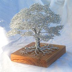 a metal tree sculpture sitting on top of a wooden block