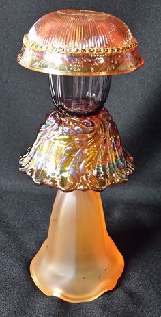 an old fashioned glass lamp on a black background with gold trimmings and a dome shade