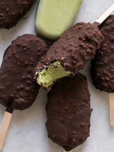 chocolate covered ice cream pops are on wooden skewers next to green and white sticks