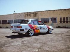 an old toyota car painted with colorful stripes