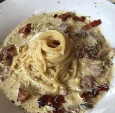 a white bowl filled with pasta and bacon