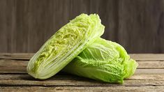 two lettuce halves sitting on top of a wooden table