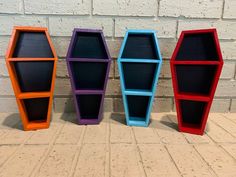 three different colored bookshelves sitting next to each other on a brick floor in front of a white brick wall