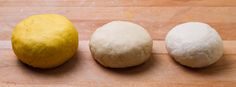 three different types of dough sitting on a wooden surface next to a yellow and white ball