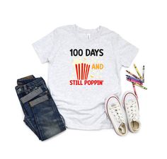 a t - shirt that says 100 days and still poppin next to some pencils