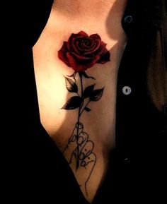 a woman's chest with a rose tattoo on her left arm and hand holding the flower