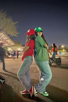 two young people are standing on skateboards in the street at night, one is hugging the other