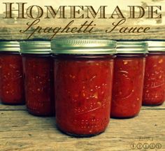 four jars of homemade jam sitting on top of a wooden table