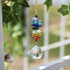 a wind chime hanging from a tree branch in front of a white picket fence