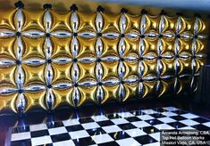 an artisticly designed wall made out of gold and black circles on a checkerboard floor