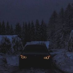 a car driving down a road in the snow at night with its headlights turned on