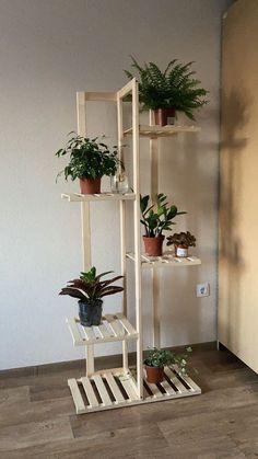 three wooden shelves with plants in them on the floor next to a wall and a potted plant