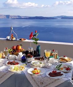 the table is set for two on the balcony overlooking the water and boats in the distance