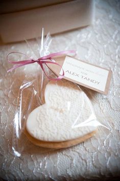 two heart shaped cookies wrapped in cellophane and tied with a pink ribbon on a table