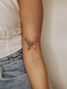 a woman's arm with a small butterfly tattoo on the left side of her arm