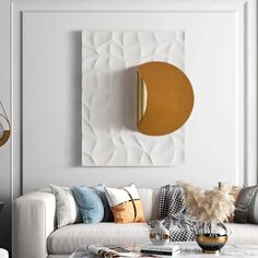 a living room with white couches and gold accents on the wall above it is an abstract painting