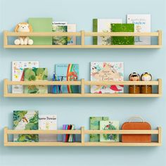 three wooden shelves with books and toys on them against a blue wall in a children's room