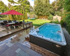 a hot tub sitting on top of a wooden deck next to a lush green field