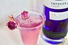 a pink drink in a glass next to a bottle