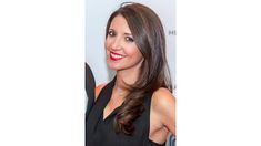 a woman with long brown hair wearing a black dress and red lipstick smiles at the camera