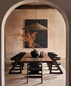 a dining room table with chairs and a vase on the table in front of an archway