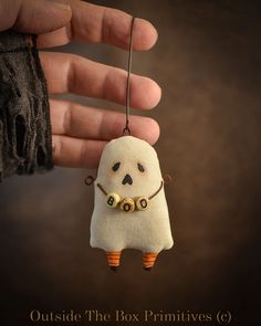 a hand holding a small stuffed toy in the shape of a ghost with two eyes