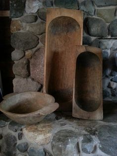 several pieces of wood sitting next to each other on a stone floor in front of a rock wall