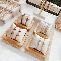 a table topped with lots of white pillows and jewelry on top of wooden trays