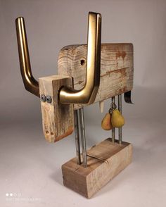 a wooden sculpture with metal handles and pears hanging from it's sides on a stand