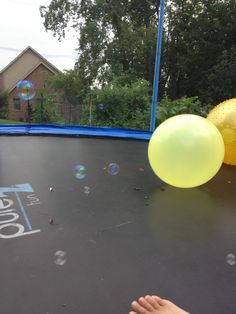 two balloons are on the trampoline and someone is holding one balloon in their hand