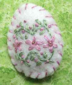 a white button with pink flowers on it sitting on a green cloth covered tablecloth