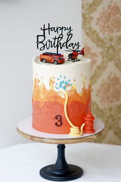 a birthday cake with two cars on top and the number three painted on it's side