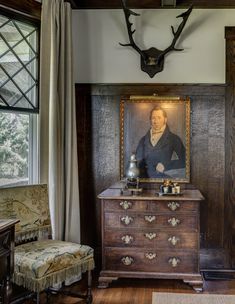 an antique dresser in the corner of a room with antlers on the wall above it