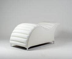 a white leather chair sitting on top of a white floor next to a gray wall