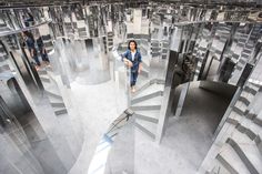 a woman standing in the middle of a room filled with mirrors