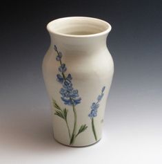 a white vase with blue flowers painted on it