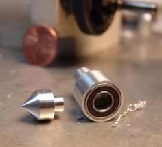 two metal objects sitting on top of a table next to a penny and a machine