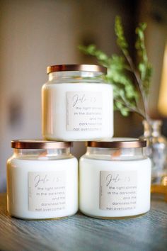 three white candles sitting on top of a wooden table