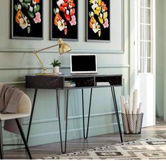 a desk with a computer on it in front of two paintings