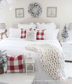 a white bed topped with lots of pillows next to a christmas tree and other decorations