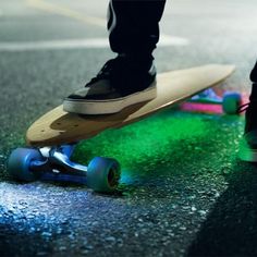 a person standing on top of a skateboard next to green and blue wheels in the street