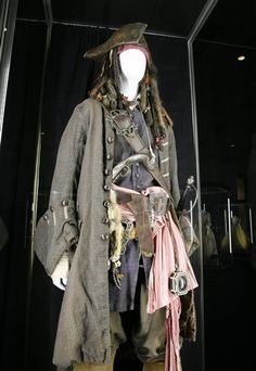 an old fashion pirate costume on display in a glass case with other items around it