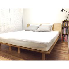 a bed with white sheets and pillows in a room next to a bookcase filled with books