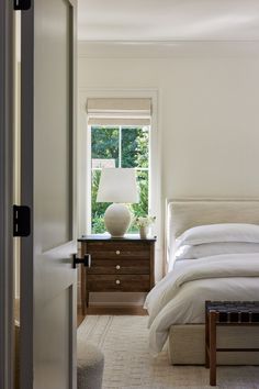 a bedroom with a bed, nightstand and lamp in the corner next to a window