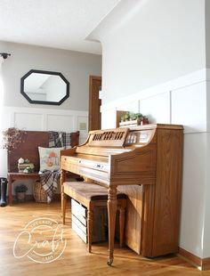 a piano sitting on top of a hard wood floor in a living room next to a mirror